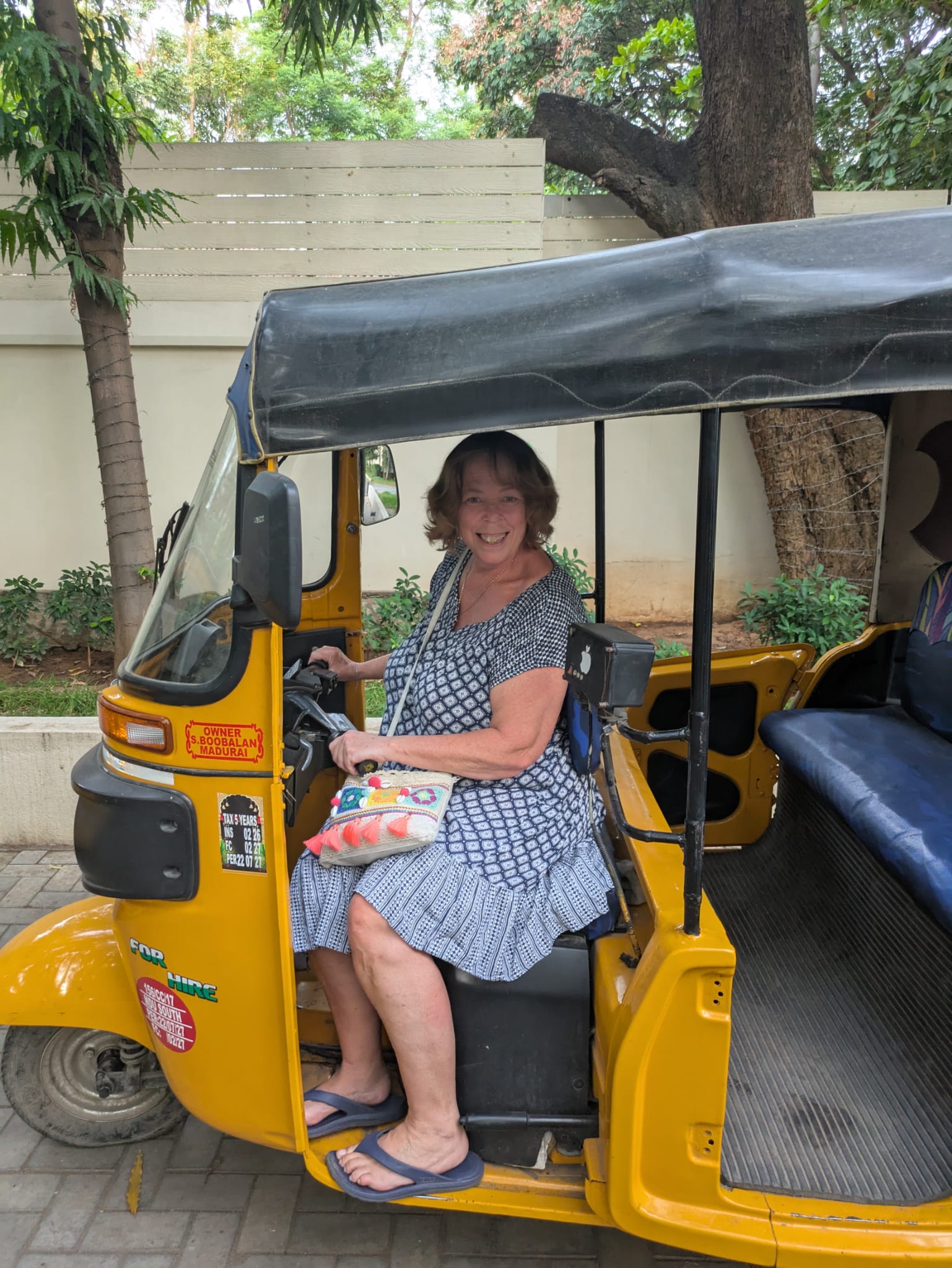 Sue sitting inside a yellow auto-rickshaw with a gray canopy.